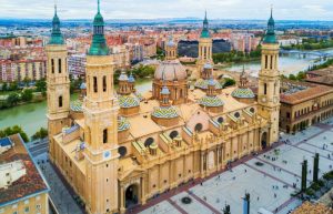 "Vista de la Plaza del Pilar en Zaragoza, un majestuoso espacio rodeado de monumentos históricos como la Basílica del Pilar y la Fuente de la Hispanidad, en el corazón de la ciudad.