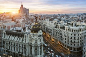 Vista de la Gran Vía de Madrid con el icónico Edificio Metrópolis, una de las calles más emblemáticas de la capital, llena de vida, comercios y arquitectura histórica.
